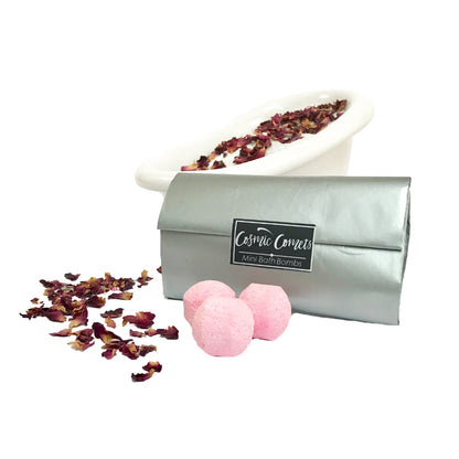 Cosmic Comets mini bath bombs placed next to a bath with rose petals, creating a colorful and relaxing spa atmosphere